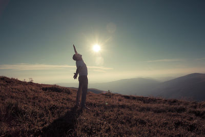 Man standing on field against sky during sunset