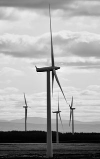 Wind turbines on field against sky