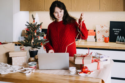 Young woman using mobile phone while sitting on table at home