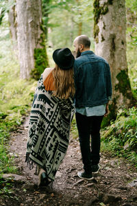 Rear view of couple walking in forest