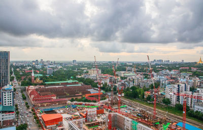High angle view of city buildings against cloudy sky
