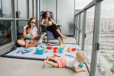 Young mothers spending time together with children babies on balcony at home. staycation 