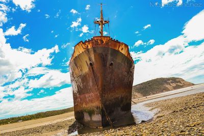 Low angle view of old rusty ship moored at seashore against sky