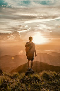 Rear view of man standing on field during sunset