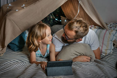 Father and son playing in a teepee tent at home.