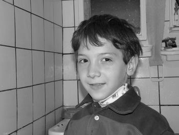 Close-up portrait of boy smiling while standing in bathroom