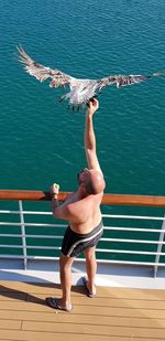 Full length of woman with arms raised against sea