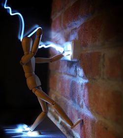 Close-up of figurine against illuminated wall