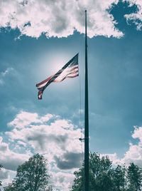 Low angle view of american flag waving against sky