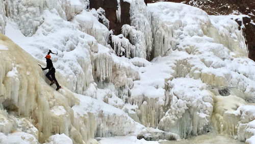 Rear view of man on snow covered rocks during winter