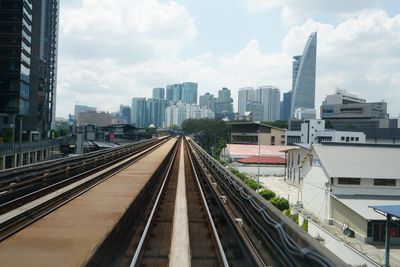 Railroad tracks amidst buildings in city against sky