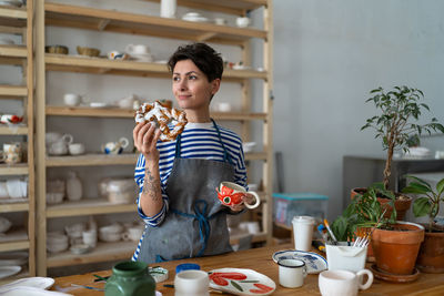 Young girl ceramist drink coffee and has snack in art studio during break from master class