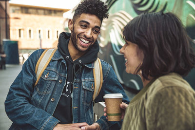 Happy young man and woman with coffee talking in the city