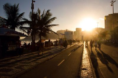 People walking on city street during sunset