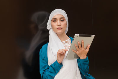 Young woman looking away while standing against black background