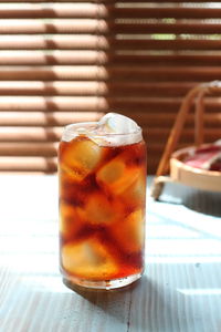 Close up of ice tea drink on the blue table and bamboo window at the background.
