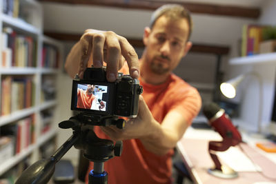 Mid adult man adjusting camera for recording video tutorial