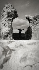 Rear view of man standing on rock by sea against sky