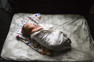 High angle view of cute newborn baby boy sleeping on bed at home