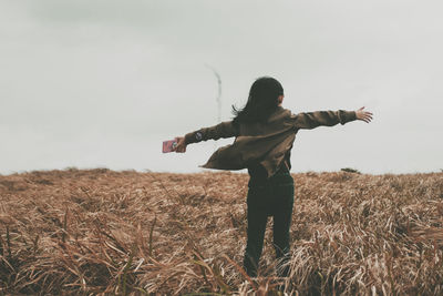 Girl standing on field against sky