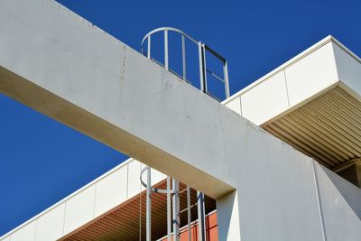 Low angle view of staircase by building against clear blue sky