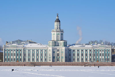 Buildings in snow covered city against clear sky