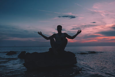 Full length of man with arms raised at beach against sky at night