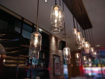 Low angle view of illuminated pendant lights hanging from ceiling in restaurant