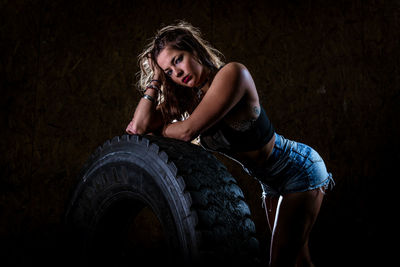 Portrait of woman standing by tire at gym