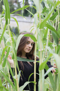 Portrait of young woman with plants in foreground