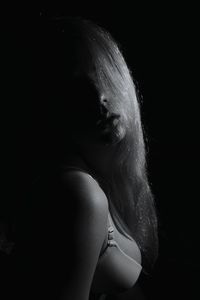 Sensuous woman with long hair standing in darkroom