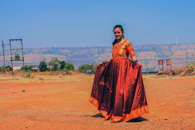 Portrait of woman standing on field against sky