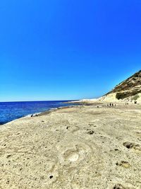 Scenic view of beach against clear blue sky
