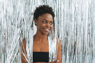 Portrait of happy beautiful young african american woman in black top on sparkly silver background