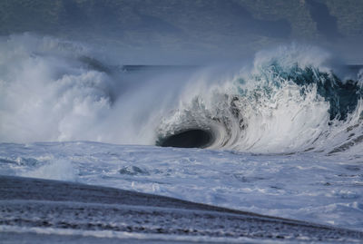 Scenic view of sea waves splashing against sky