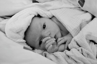 Close-up of new born baby wrapped in blanket lying on bed