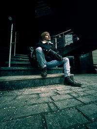 Young man sitting on footpath in city