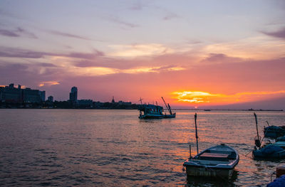 Sailboats in sea against sky during sunset