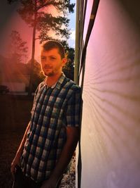 Portrait of smiling man standing against sky during sunset