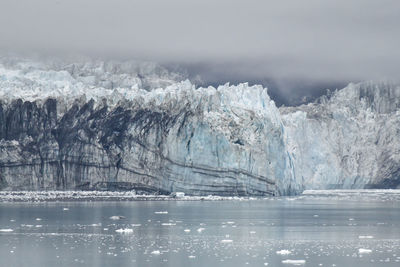 Ancient glacier and foggy dramatic sky in alaska ocean bay