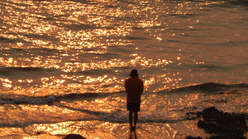 Rear view of boy on beach at sunset