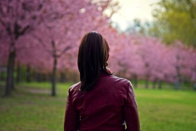 Rear view of woman standing against pink flower