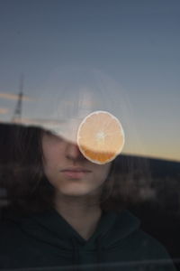 Woman and orange fruit seen through glass