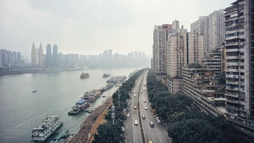 High angle view of city street and buildings by river against sky