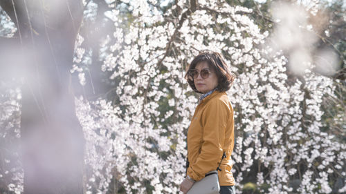 Young woman standing against trees