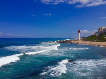 Lighthouse by sea against sky