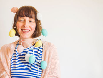 Smiling woman with string light against wall