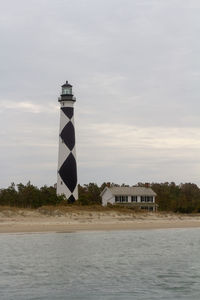 Lighthouse by sea against sky