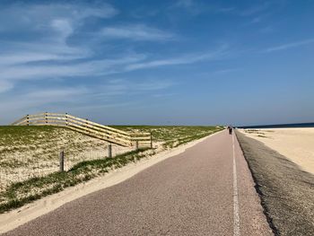 Empty road amidst land against sky