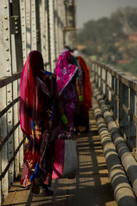 Rear view of women walking on bridge